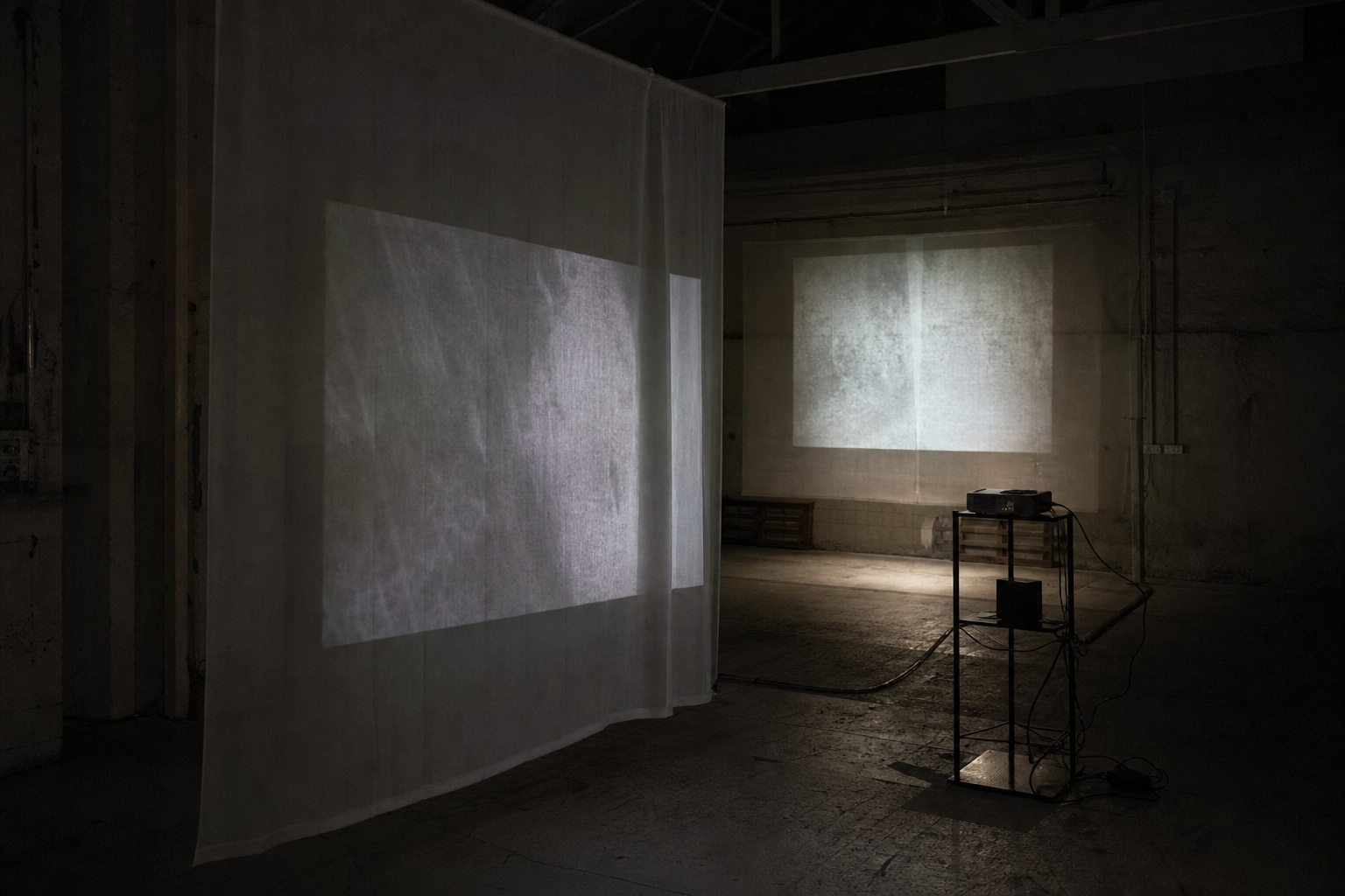 Translucent scrims and projected light in a dark industrial workshop