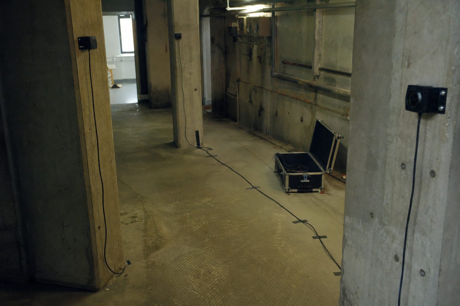 Small transducers, cables and a flight case in a concrete utility room